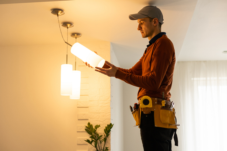 Electrician worker installation electric lamps light inside apartment. Construction decoration concept.